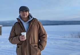 first nation man standing in snow near frozen lake