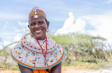 A portrait of a young woman wearing a large beaded necklace and crown.