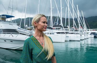 Woman stands before recreational boats in Seychelles.