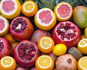 A colorful composition of sliced-open colorful citrus, pomegranates, mangoes and pineapples.