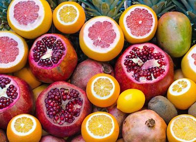 A colorful composition of sliced-open colorful citrus, pomegranates, mangoes and pineapples.