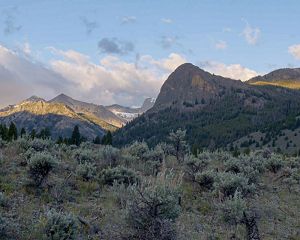 Large mountain peaks at sunrise with sagebrush hills in the foreground.