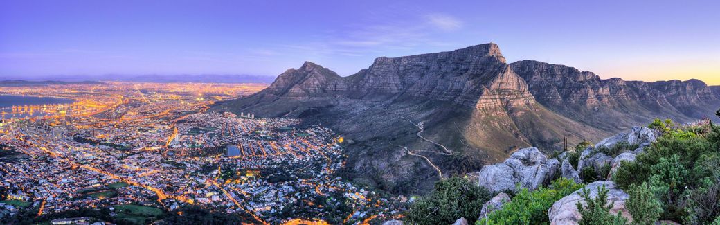 Elevated view of city lights at the foot of a ridge of rugged mountains.