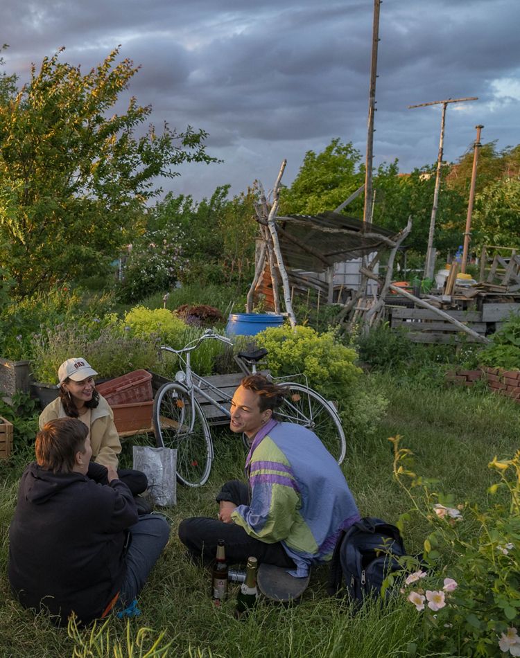 Three Berlin friends sitting in a community garden.