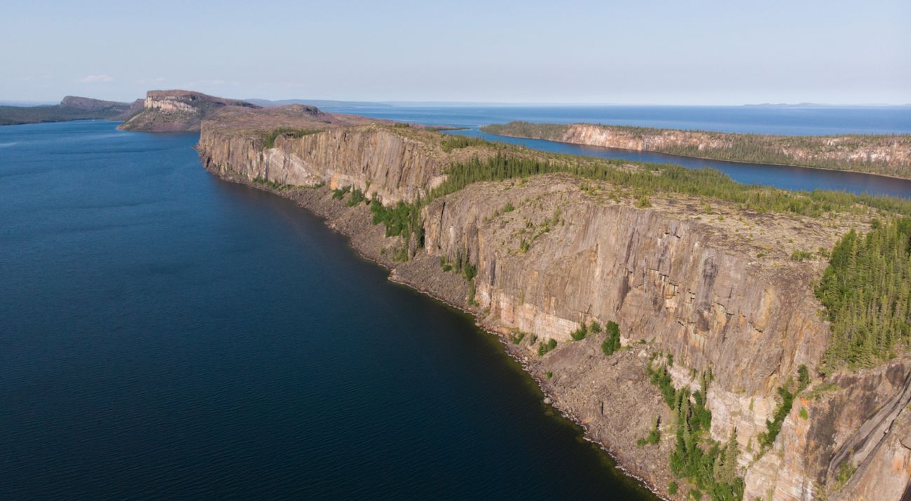 An aerial view of a long chain of tall rocky cliffs next to a large body of water.