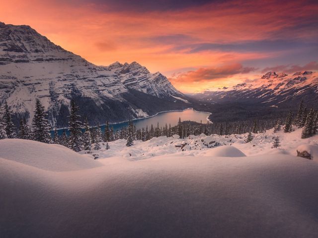 Glowing clouds illuminate snowy mountain lake.