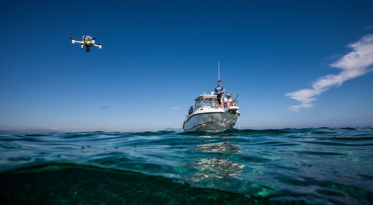 2 people standing on an anchored white power boat.