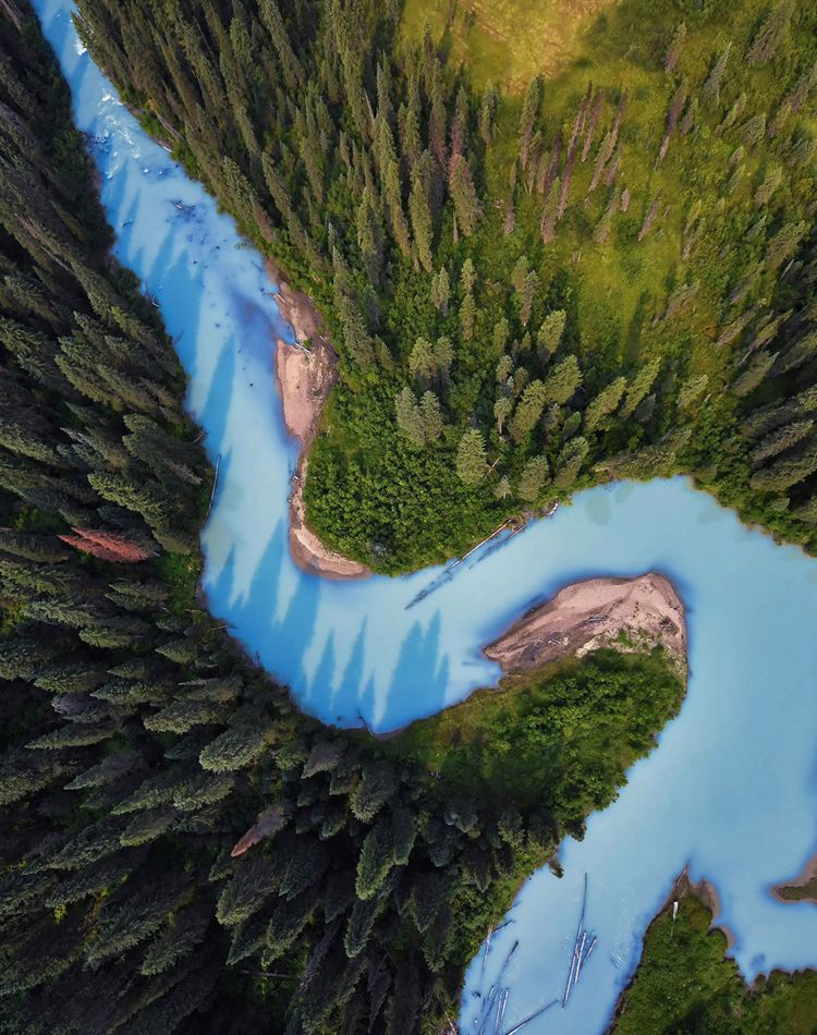 Aerial view of a sky-blue river running through forest.