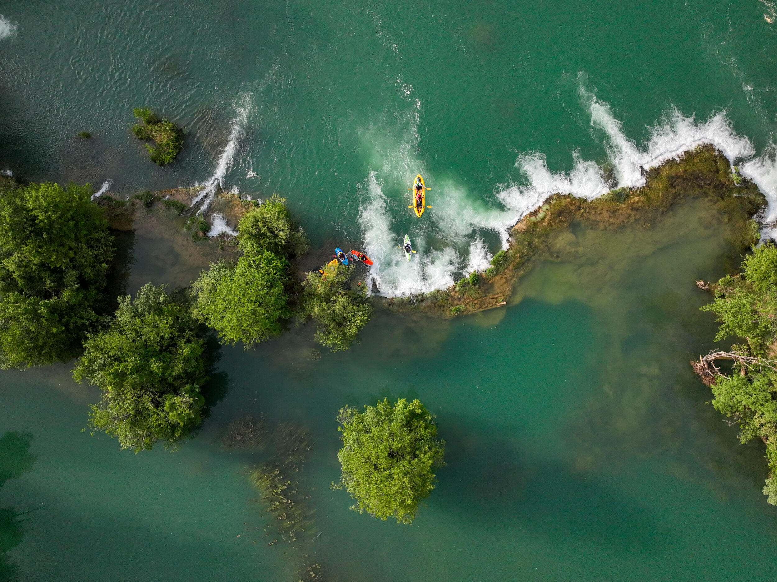 aerial view of clear-water river with kayaks.